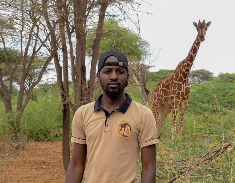 Raymond Owino with giraffe in background